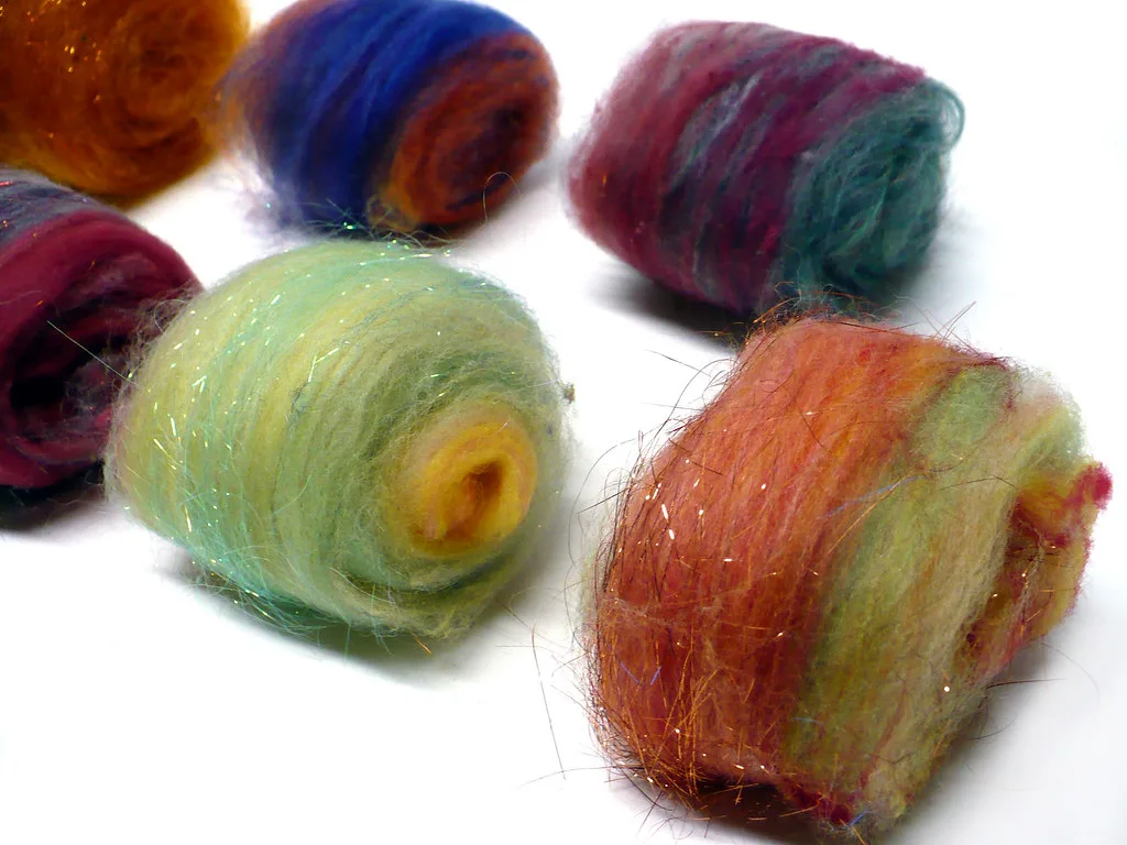 Small rolled wool batts in orange, blue, teal, red and green, with fine glittering strands carded through them
