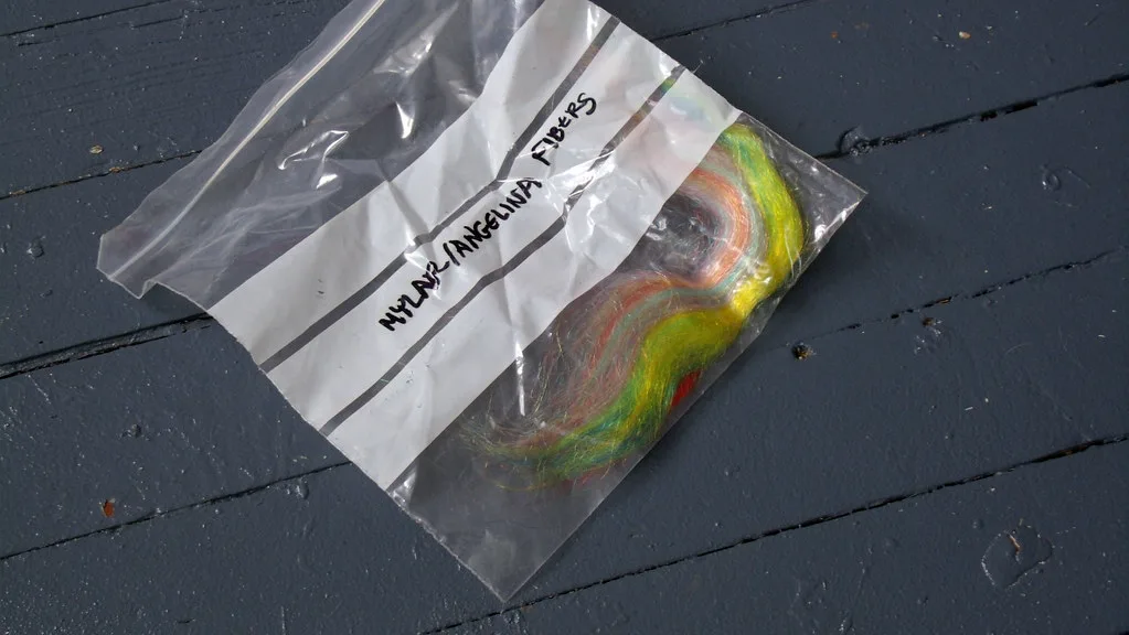 A small plastic bag of loose multicoloured Angelina sparkle fibre labelled mylar and Angelina fibers