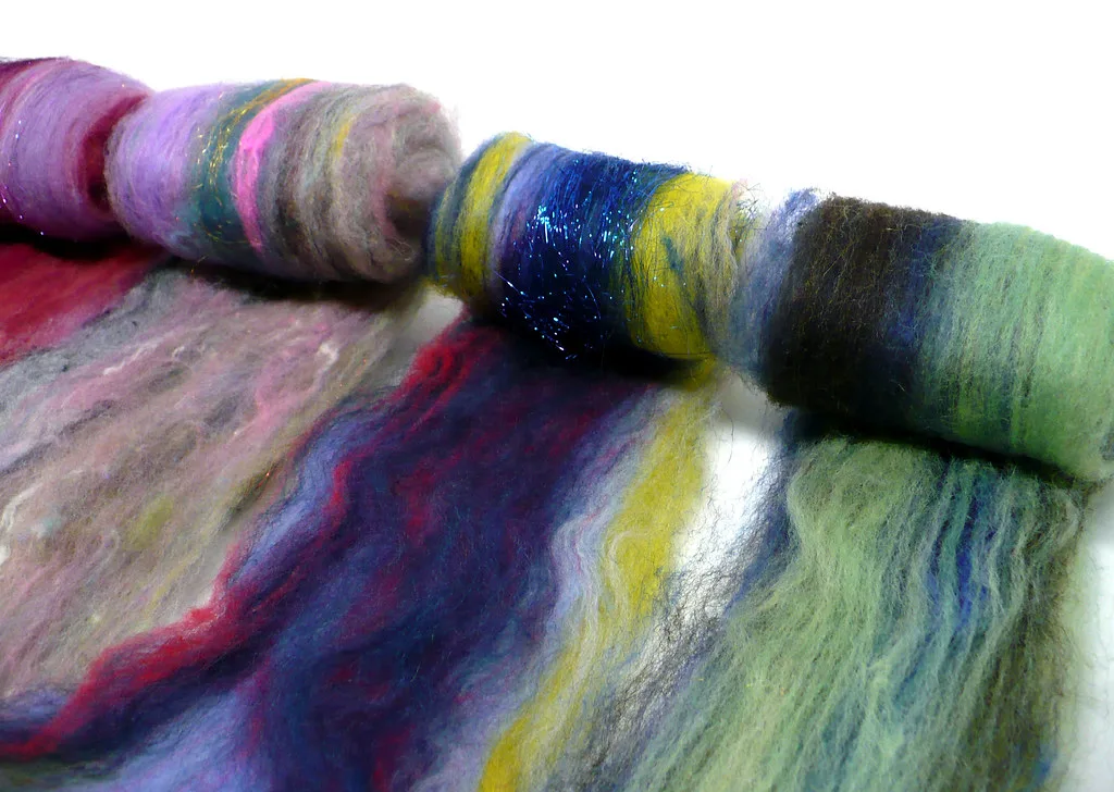 Rolled carded wool batts in purple, blue, yellow and green with glittering Angelina sparkle running through them