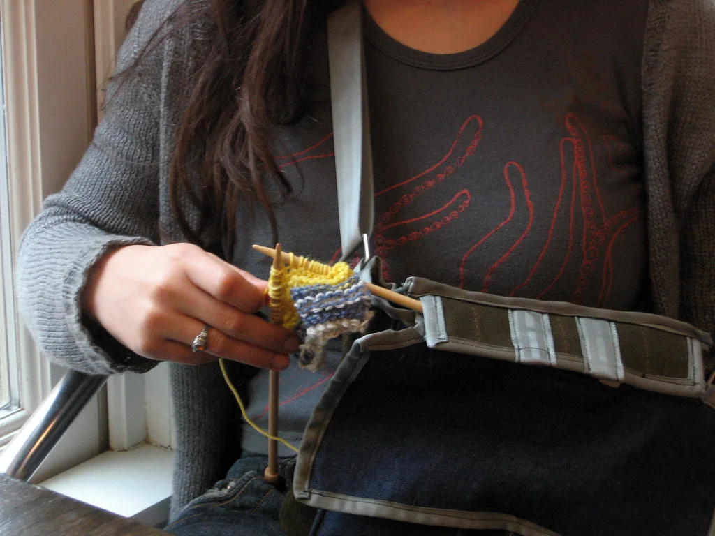A knitter part-way through a piece, needles in hand