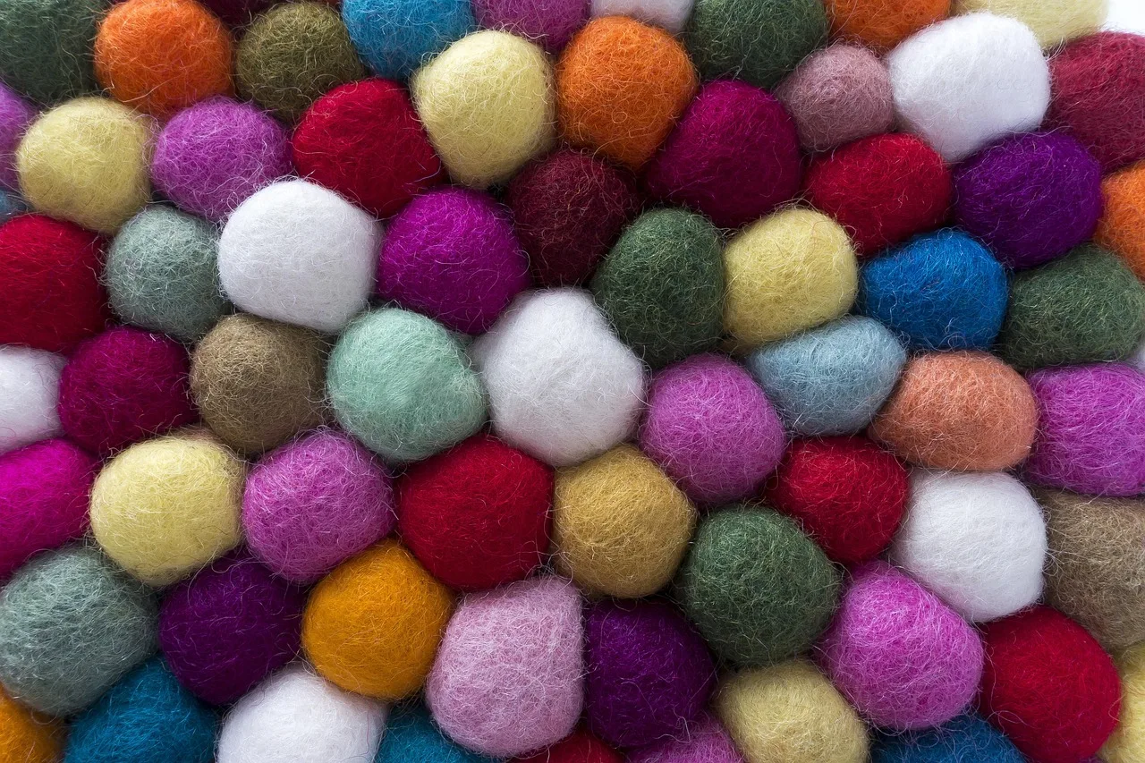 Close-packed felted wool balls in many colours, the surface of a felt ball rug