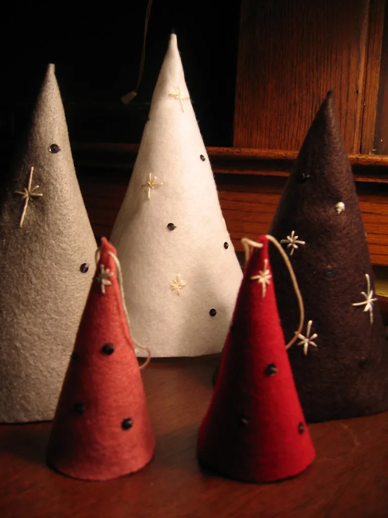 Five felt cone trees in gray, white, dark brown and red, decorated with embroidered stars and small beads