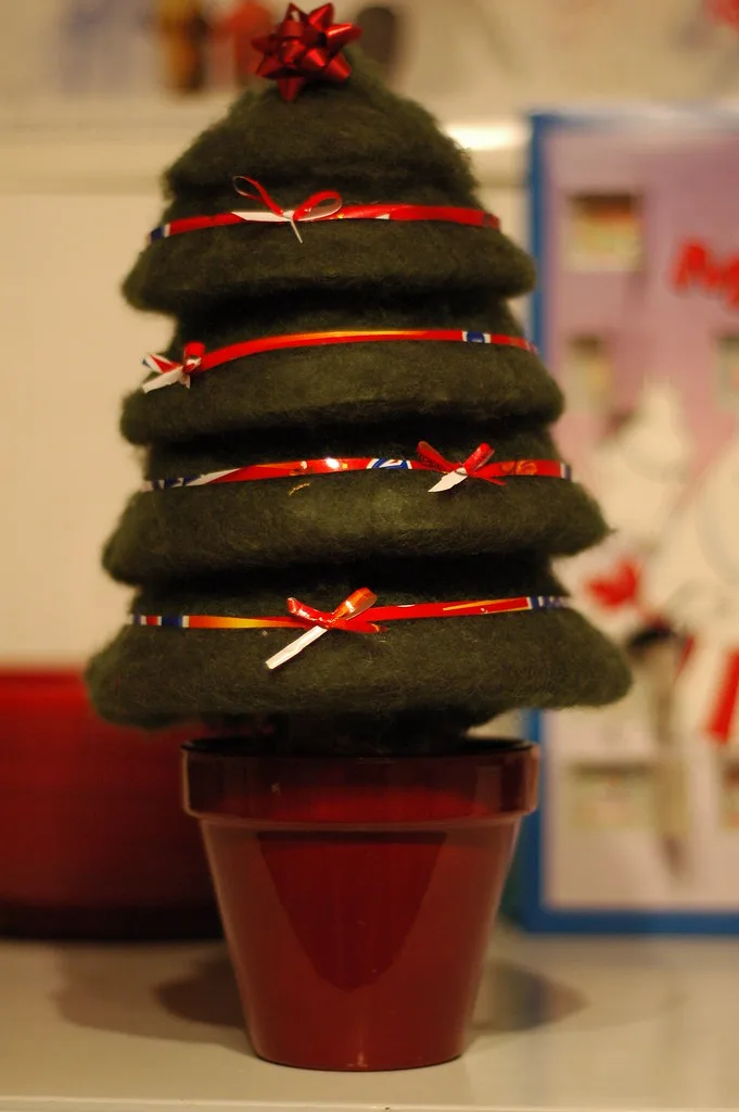 A small tree made from stacked circles of dark green felt banded with red ribbon, set in a red flowerpot