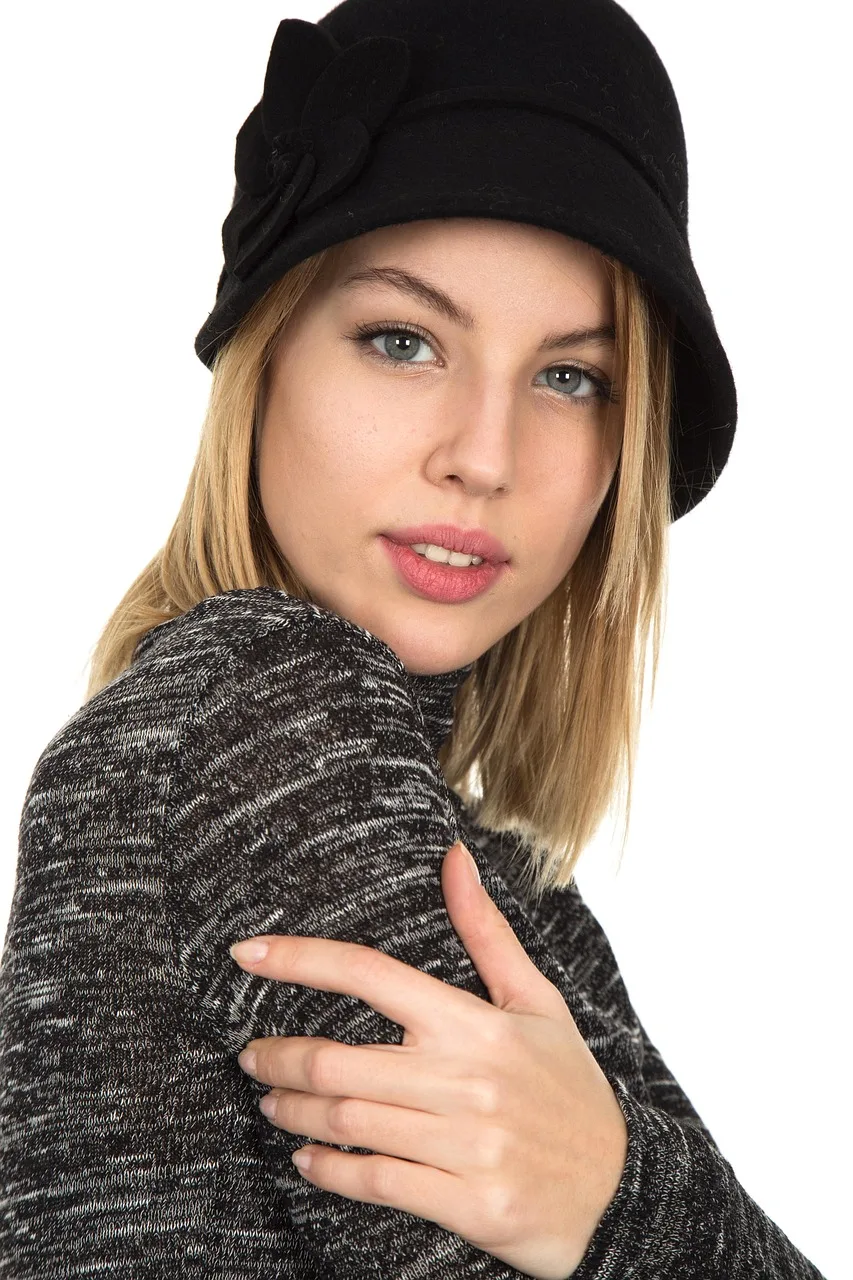 A woman with shoulder-length blonde hair in a black felt cloche with a felt flower on one side