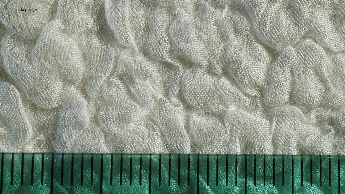 Close view of cream nuno felt, its surface rippled into small puckers where the wool shrank against the fabric