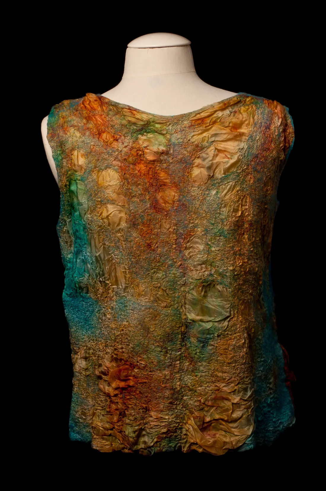 The back of a sleeveless nuno felted top in greens, golds and rust on a dress form