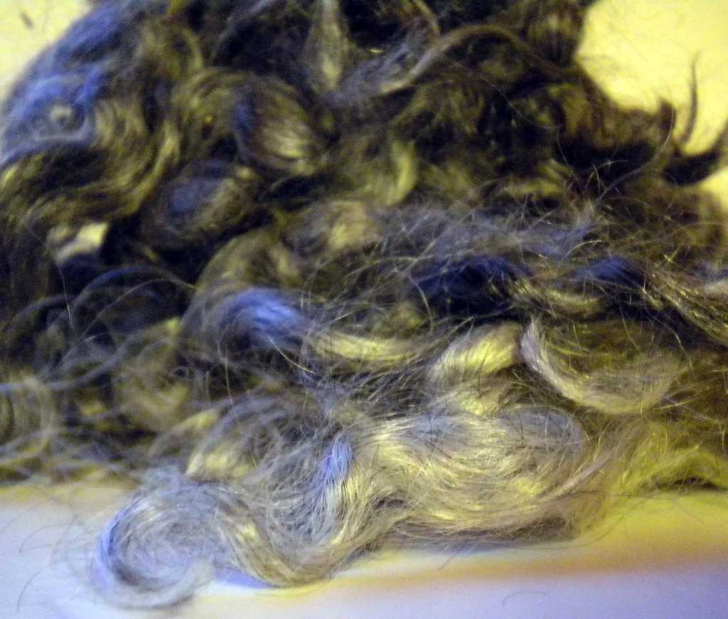 A pile of dyed dark silver mohair locks with glossy, wavy curls