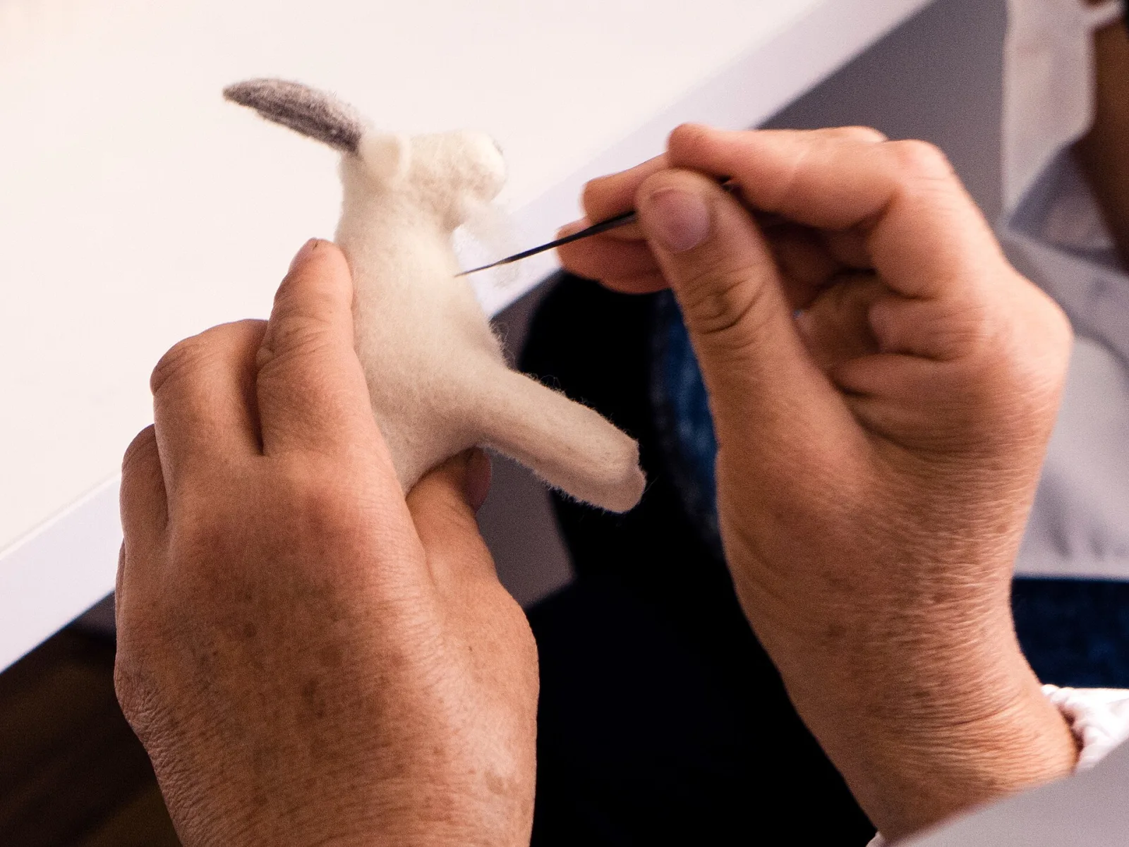 Close view of a barbed felting needle entering wool