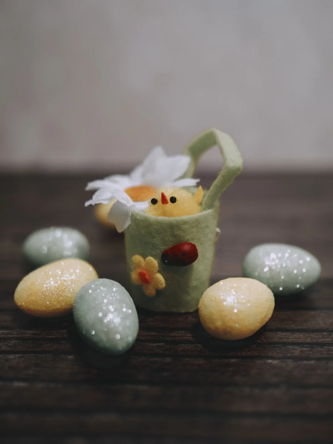 A felt Easter basket holding a small chick and speckled eggs