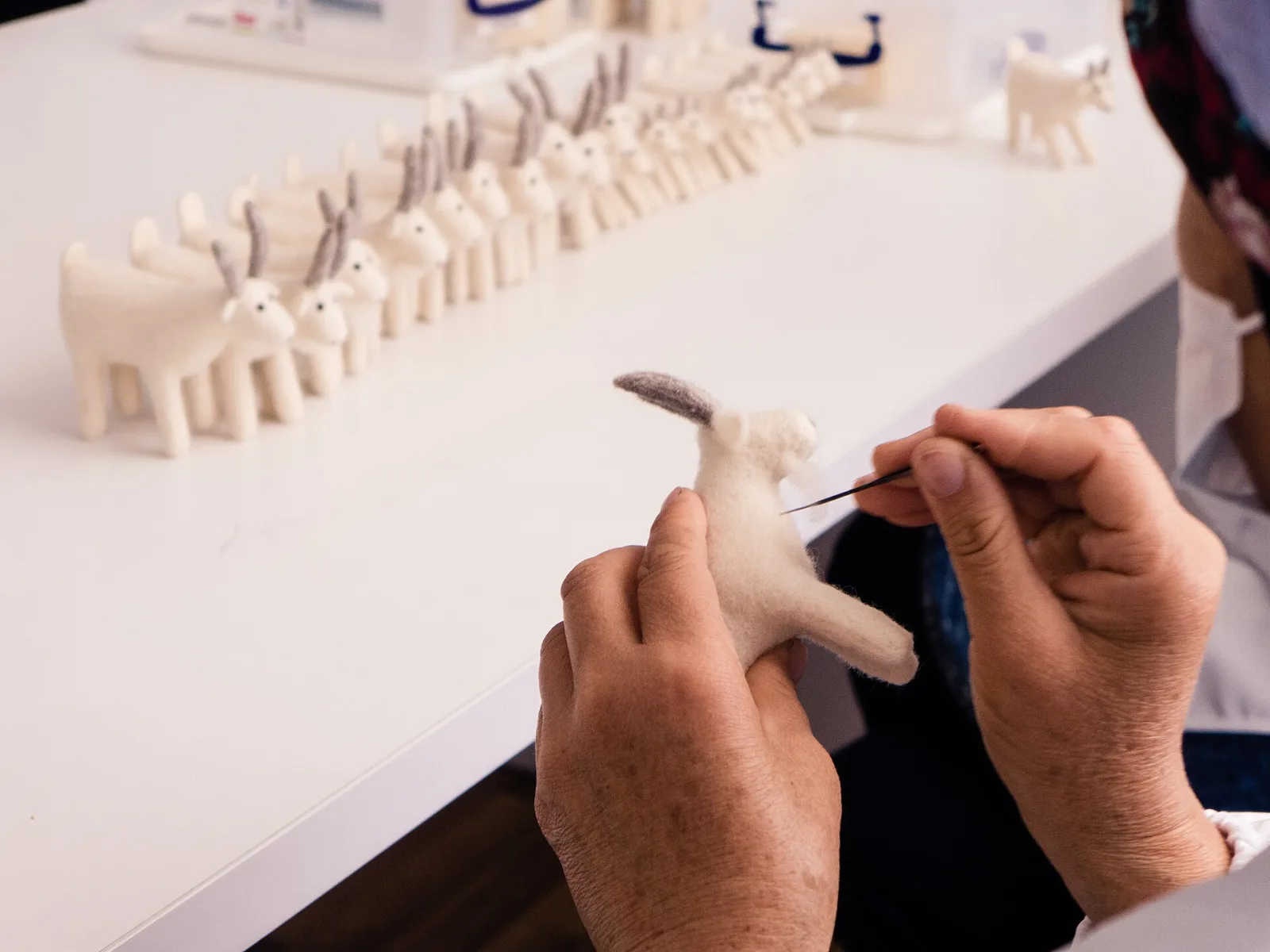 A felting needle being worked into loose wool on a foam pad
