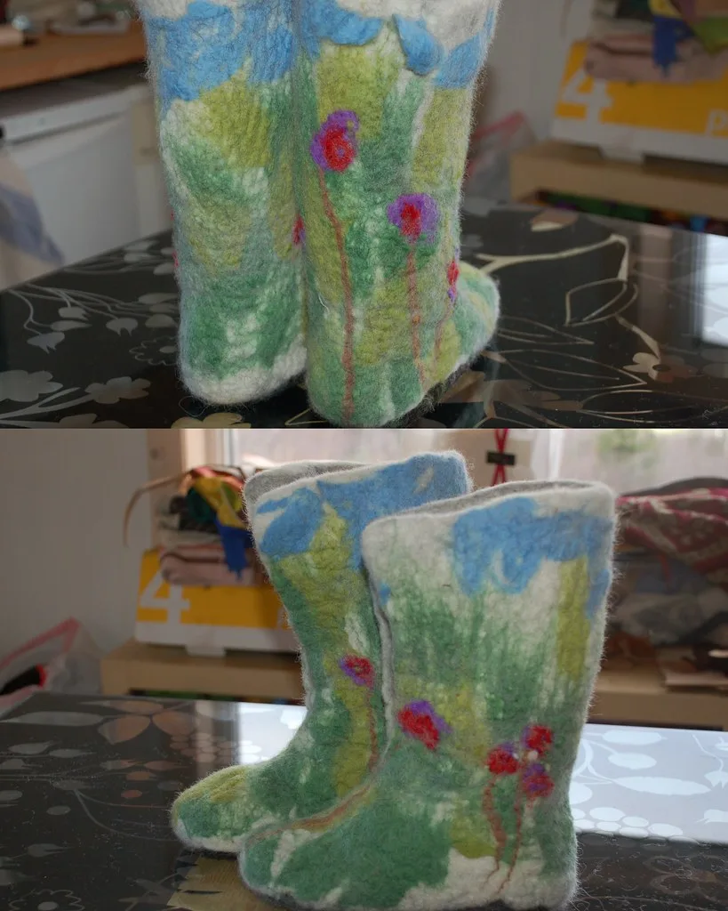 Two views of a pair of handmade wet felted boots in pale green with a felted-in meadow pattern of flowers and blue sky
