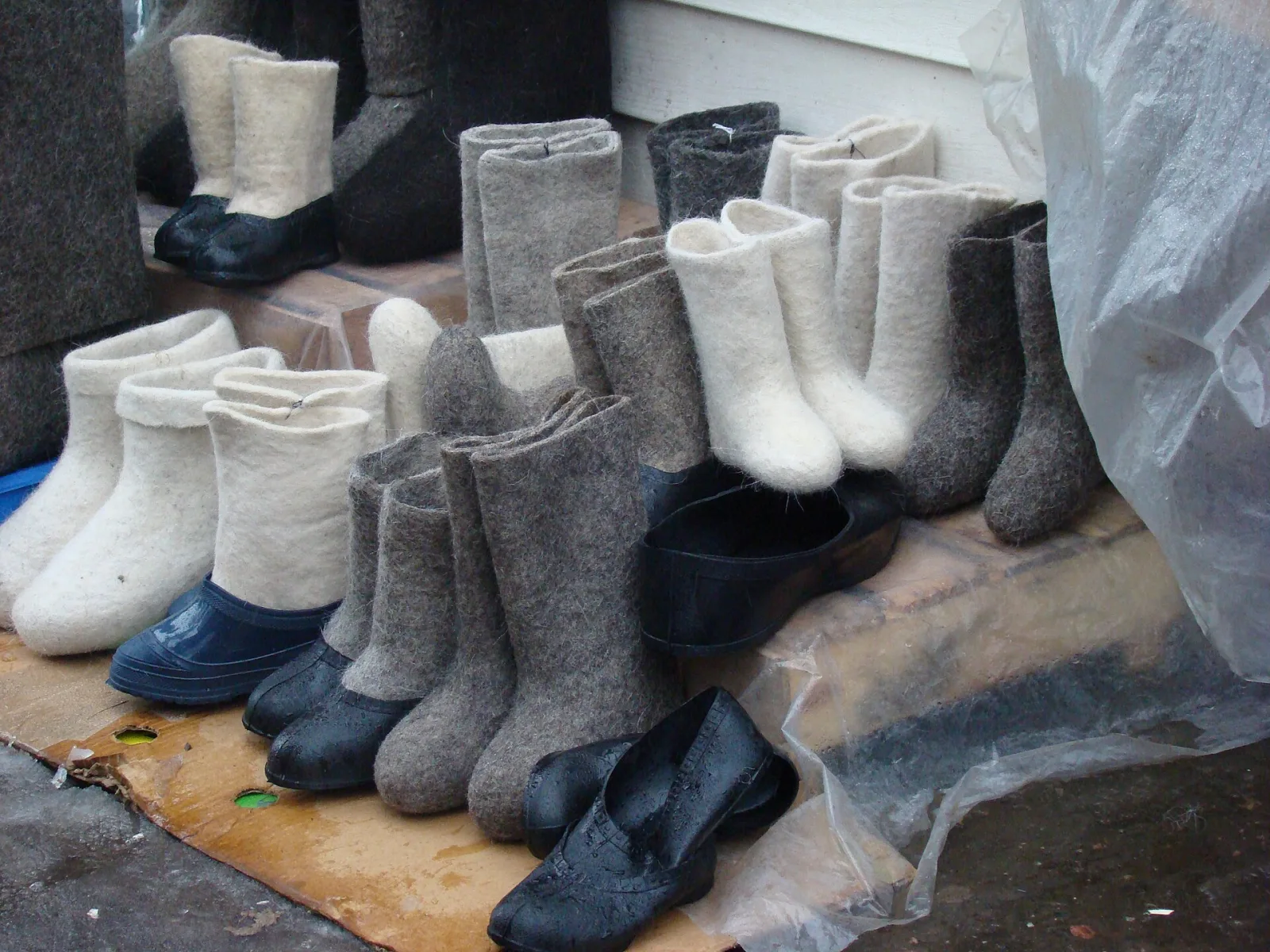 Rows of white and gray valenki, traditional felted wool boots, some fitted with black rubber galoshes